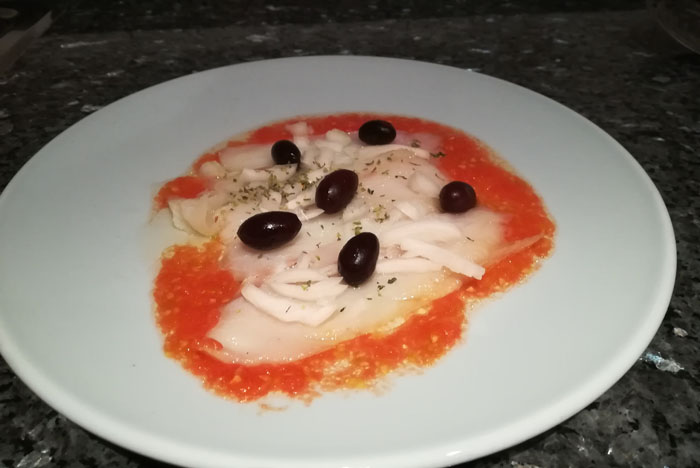 finas lonchas de bacalao con cebolleta y aceitunas sobre tomate 