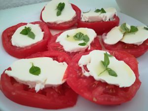 rodajas de tomate, queso mozzarela y hojas de albahaca