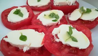 rodajas de tomate, queso mozzarela y hojas de albahaca