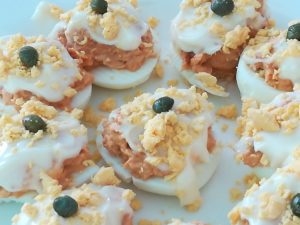 Huevos rellenos decorados con mayonesa, yema y alcaparras
