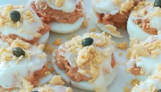 Huevos rellenos decorados con mayonesa, yema y alcaparras